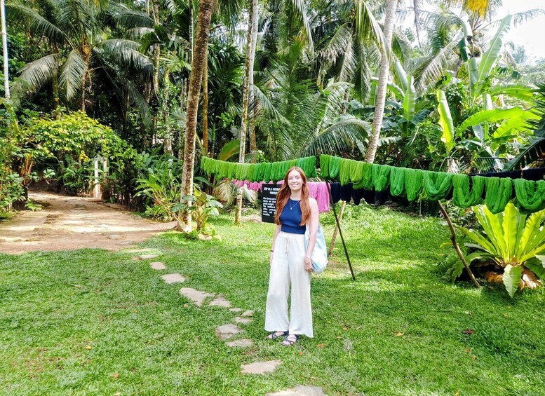 A person standing in a lush garden with a clothesline and a signboard. 5