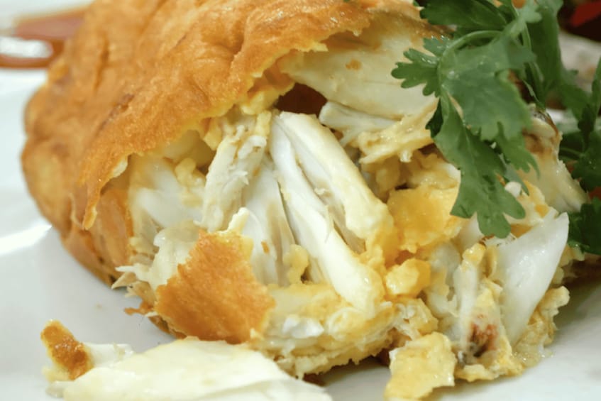A close-up of a stuffed pastry with visible egg filling and a garnish of parsley. 5