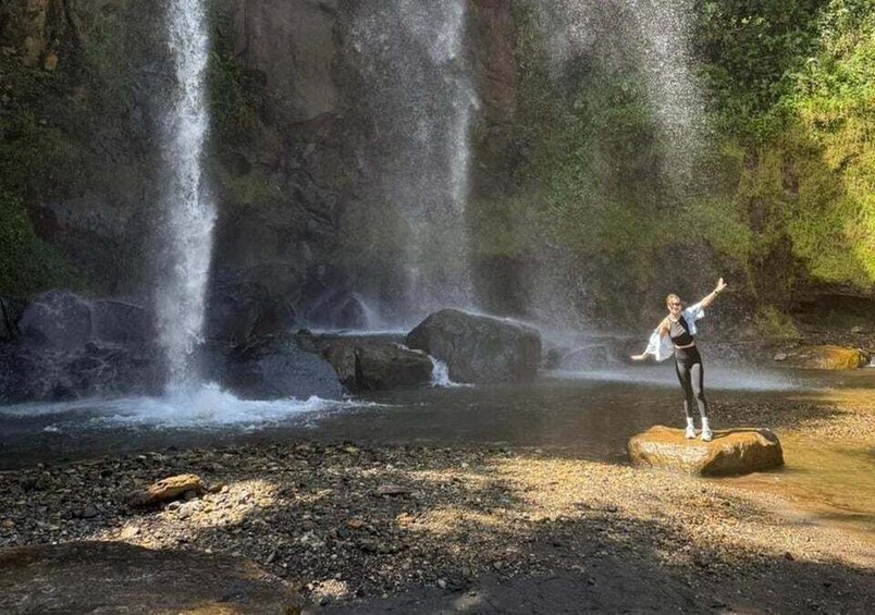 A waterfall, a person standing on a rock, and a river. 3