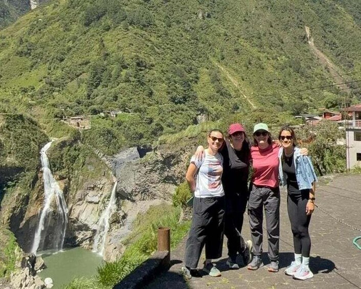A group of people standing by a waterfall with a mountainous backdrop. 4