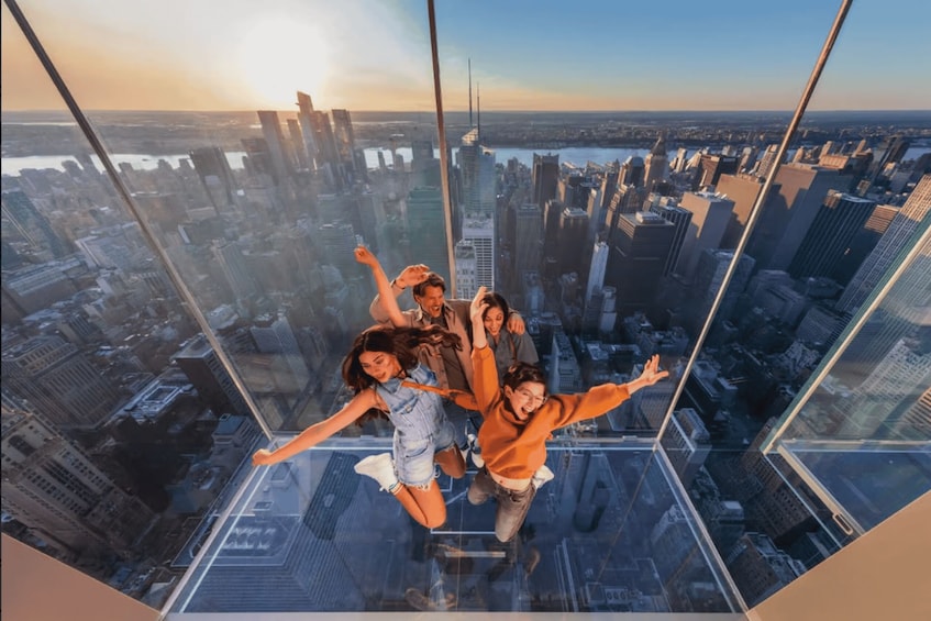 A group of people jumping on a glass floor high above a cityscape. 1
