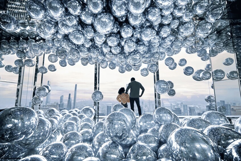 A cityscape with numerous reflective spheres suspended above. 5