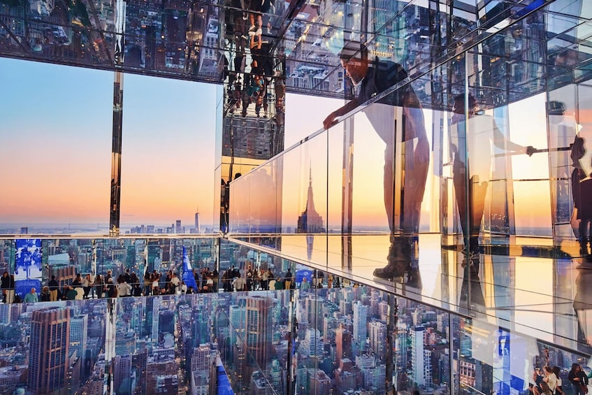 A glass observation deck with a cityscape view, including a prominent skyscraper. 2