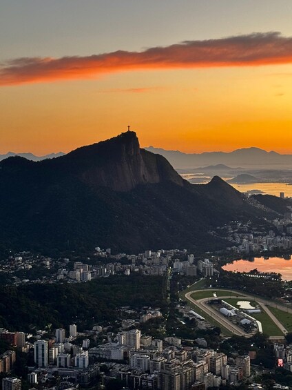 A cityscape with a prominent mountain and a body of water reflecting the sunset. 1