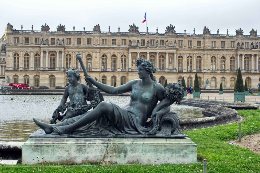 A statue of a woman and child by a fountain in front of a large historic building. 4