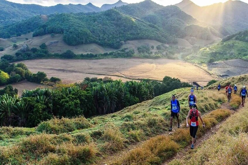 A group of people hiking on a trail surrounded by lush greenery and rolling hills. 2