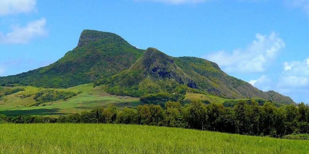 A mountain with lush green slopes and a clear blue sky. 1