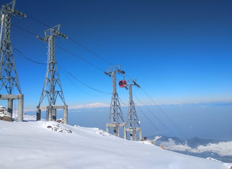 A snowy mountain with a ski lift and power lines. 2
