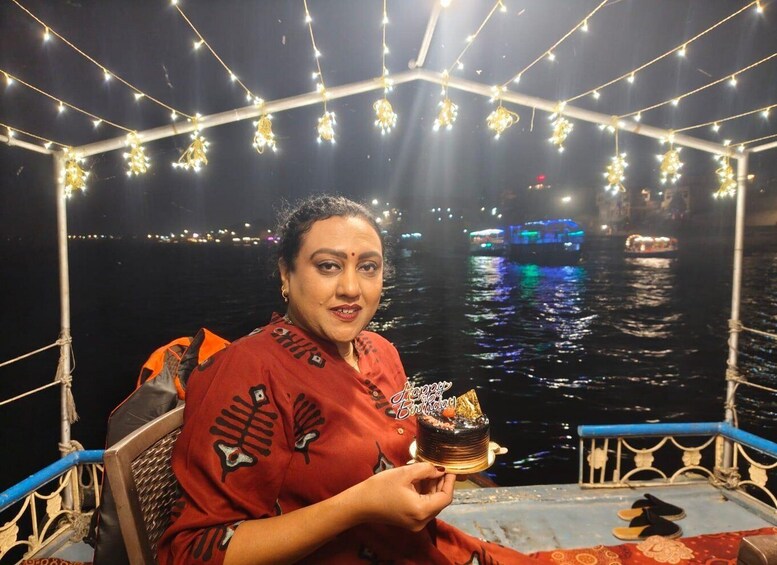 Una persona sosteniendo un pastel en un barco con luces de adorno colgando. 4