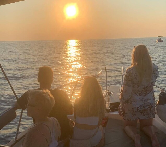 A boat with people on a calm sea during sunset. 1