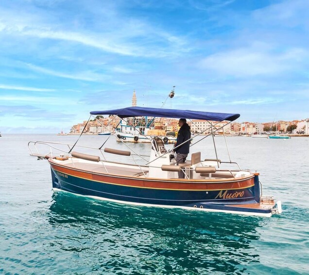 A boat named 'Muoro' anchored in calm waters with a clear sky and a distant cityscape. 4