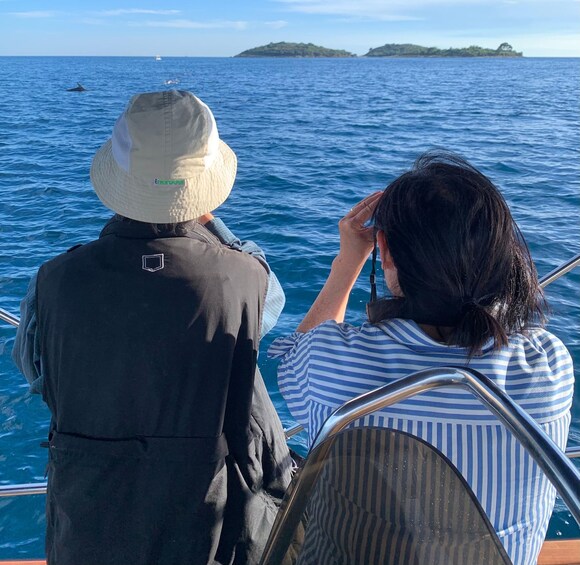Two people on a boat, one wearing a hat, looking at the sea. 5
