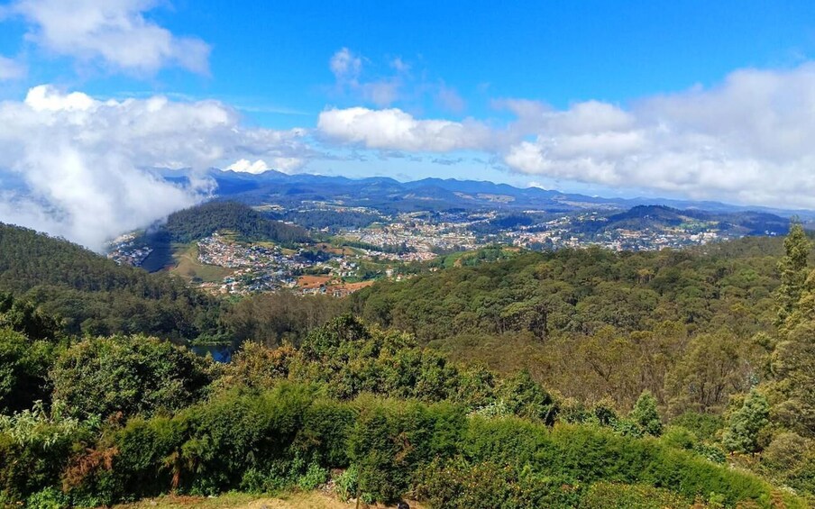 A mountainous landscape with a town nestled in the valley, surrounded by dense forests and a lake. 5