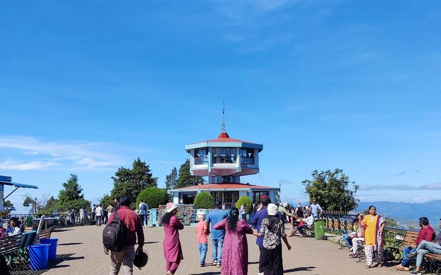 A tower with a red roof, surrounded by people and greenery. 4