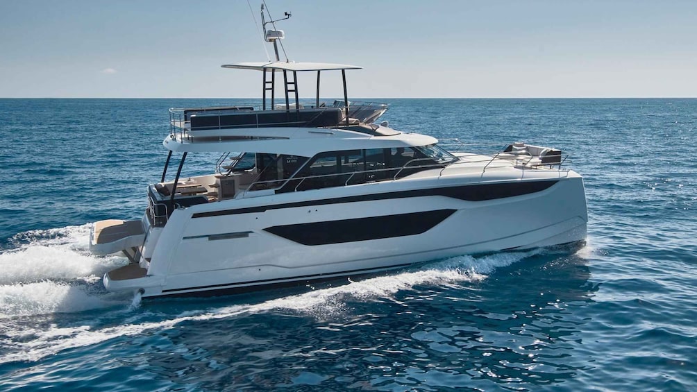 A white yacht with a cabin and deck seating, sailing on a calm sea. 1