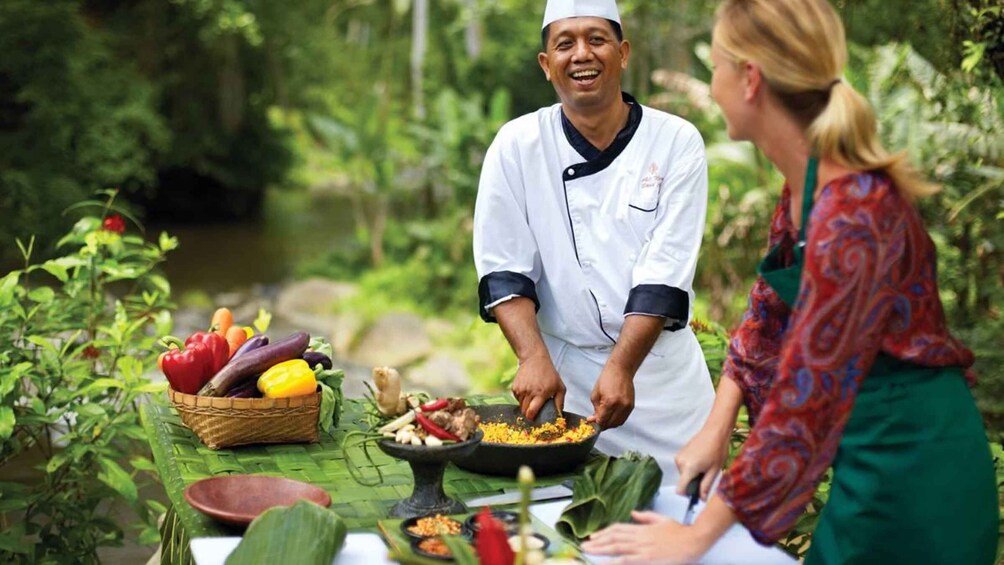 A chef preparing food outdoors with fresh vegetables and a river in the background. 1