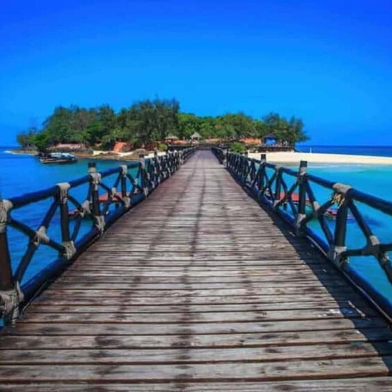 A wooden pier leading to a tropical island with clear blue waters. 5