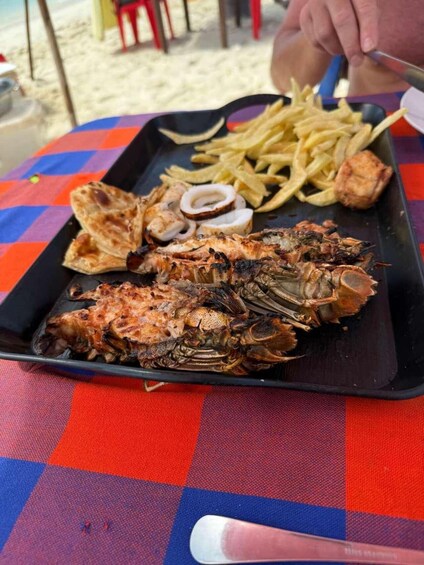 En grillad hummermusling på ett svart fat, serverad med pommes frites och tunnbröd. 4