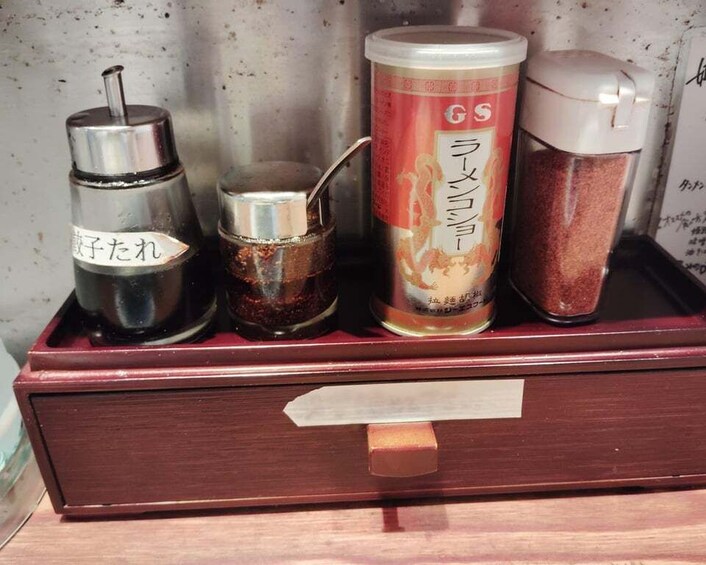 A wooden box containing four condiment containers with Japanese labels. 5
