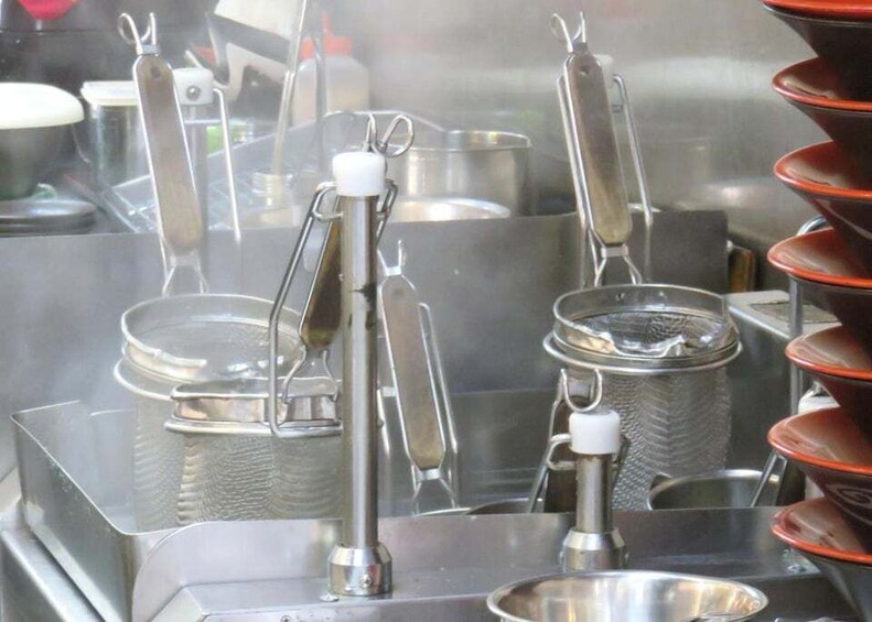 A kitchen with stainless steel equipment, including pots, pans, and a grater. 3