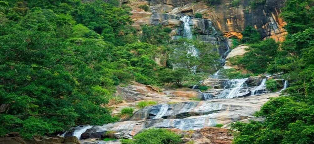 A multi-tiered waterfall surrounded by dense green forest. 3