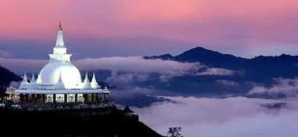 A white temple with a spire, surrounded by clouds and mountains. 4