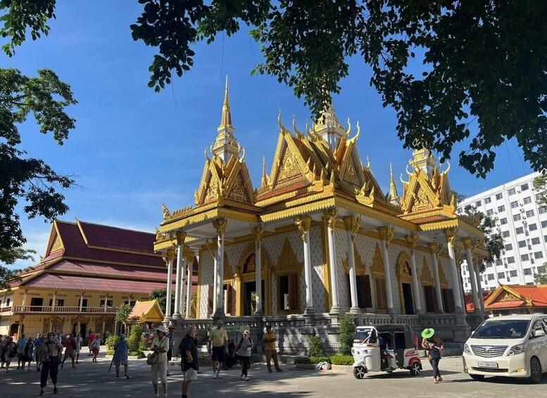 A golden temple with intricate architecture and a red-roofed building nearby. 3