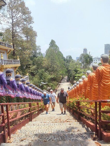 A pathway flanked by rows of monk statues ascending a stone staircase. 4