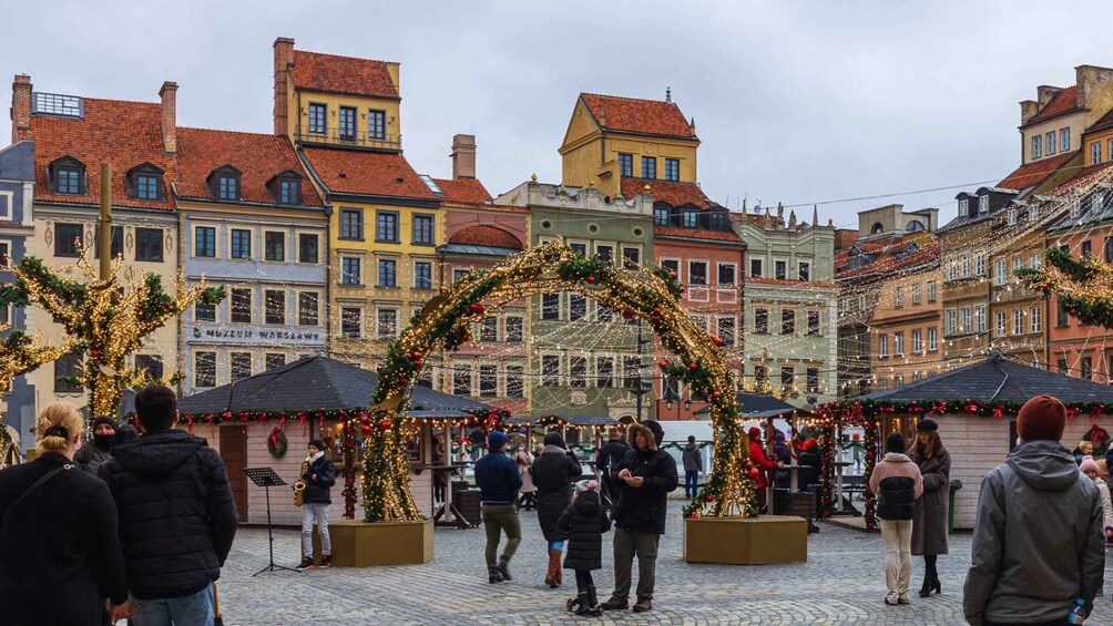 A festive market with people, decorated stalls, and a Christmas tree. 3