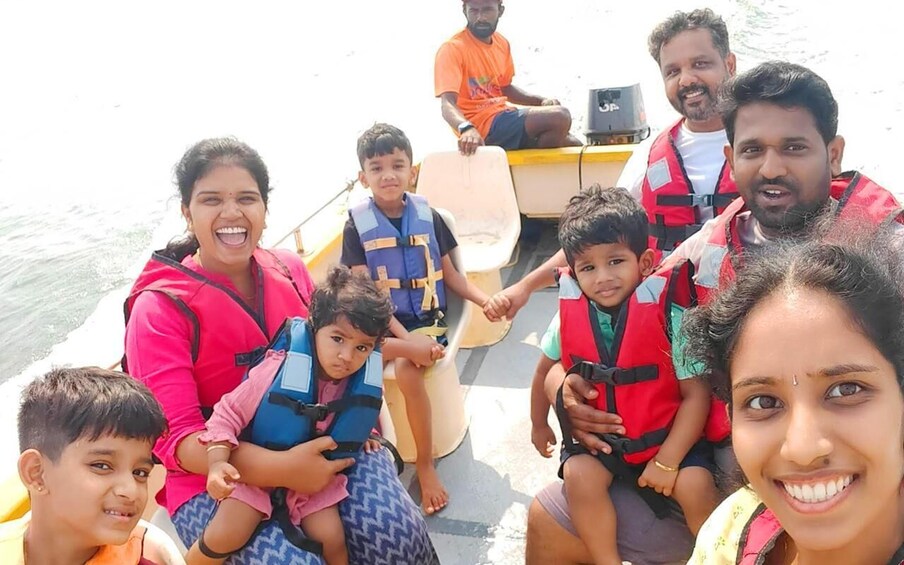 A group of people on a boat wearing life jackets, with a calm body of water in the background. 3