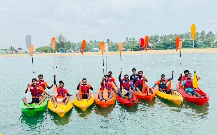 A group of people in colorful kayaks on a calm body of water, with paddleboards lined up behind them. 2