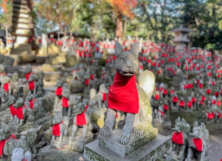 A stone statue of a bear wearing a red garment, surrounded by numerous similar statues with red ribbons. 1