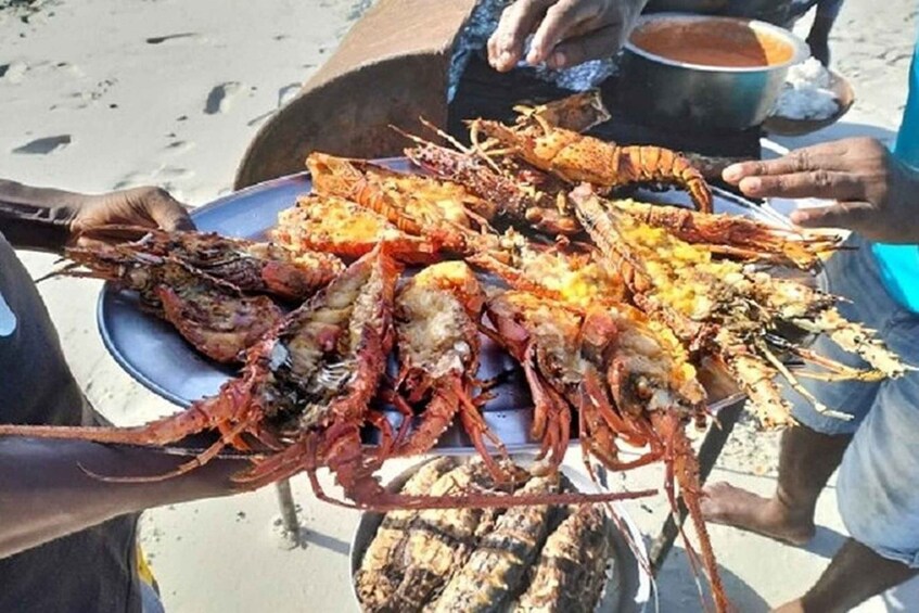 A person holding a large plate of cooked lobsters. 2