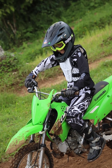 A person riding a green dirt bike on a trail. 1