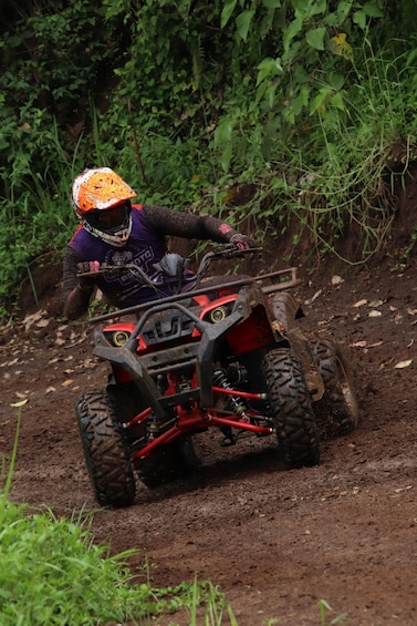 A person riding a red ATV on a dirt path surrounded by greenery. 5