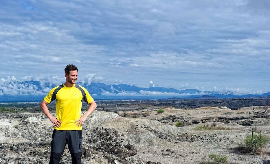 A person standing on rocky terrain with a mountainous landscape in the background. 3