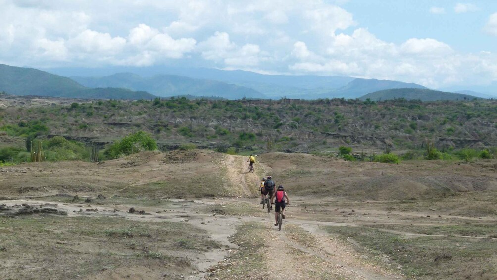 A group of cyclists on a dirt path with a mountainous landscape in the background. 5