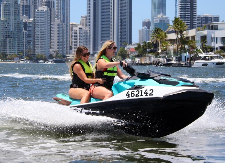 Two people on a jet ski with a city skyline in the background. 4