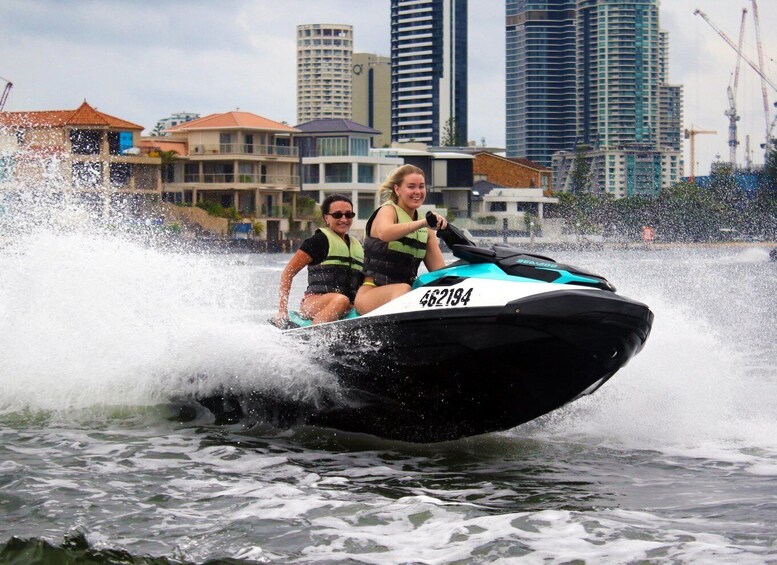 Two people on a jet ski with a cityscape in the background. 5