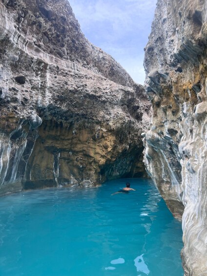 A person swimming in a natural pool surrounded by rocky cliffs. 4
