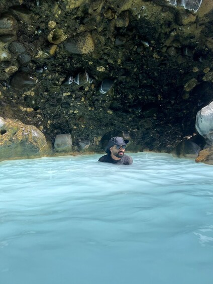 A person in a natural hot spring surrounded by rocks. 1
