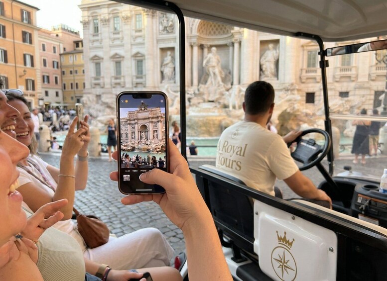 A tour bus with a person taking a photo of a historic fountain. 2