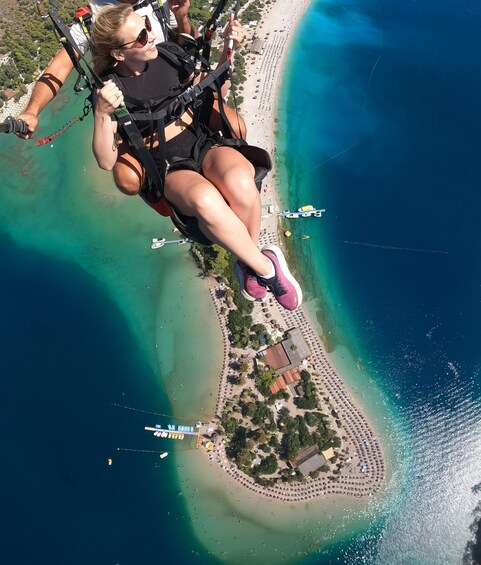 A person bungee jumping from a high point above a beach with clear turquoise waters and a small island with buildings. 5