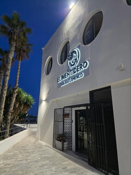 A building with a sign reading 'El Mentidero Tablao Flamenco' and palm trees in the background. 5