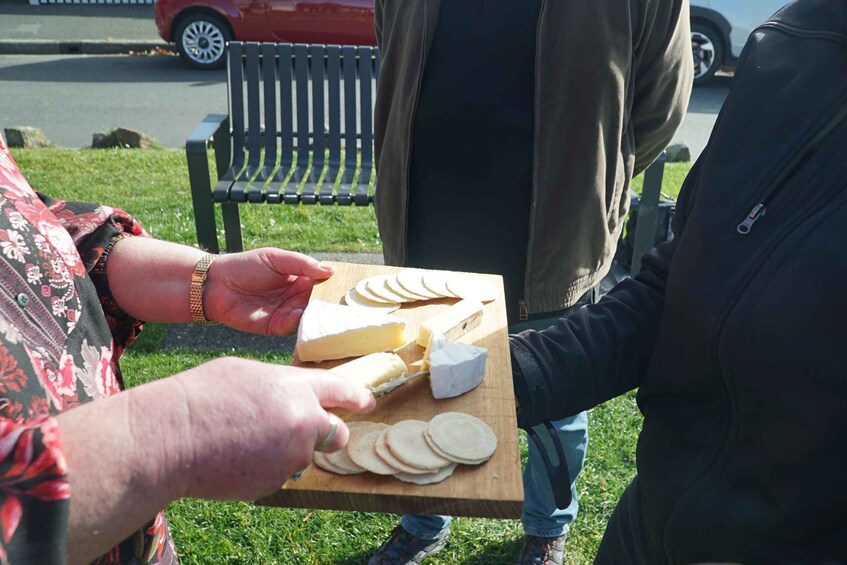 A person holding a wooden board with cheese and crackers. 3
