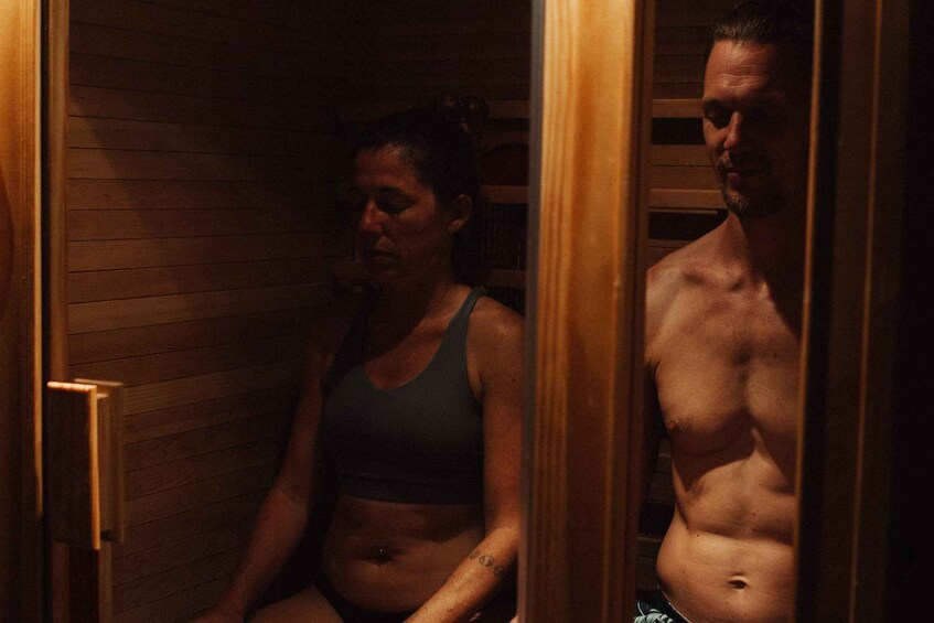 A person sitting in a wooden room with a mirror reflecting another individual. 2