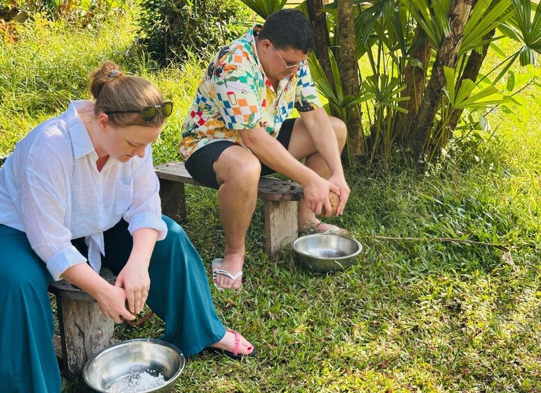 Two people sitting on a bench outdoors, one holding a bowl. 1