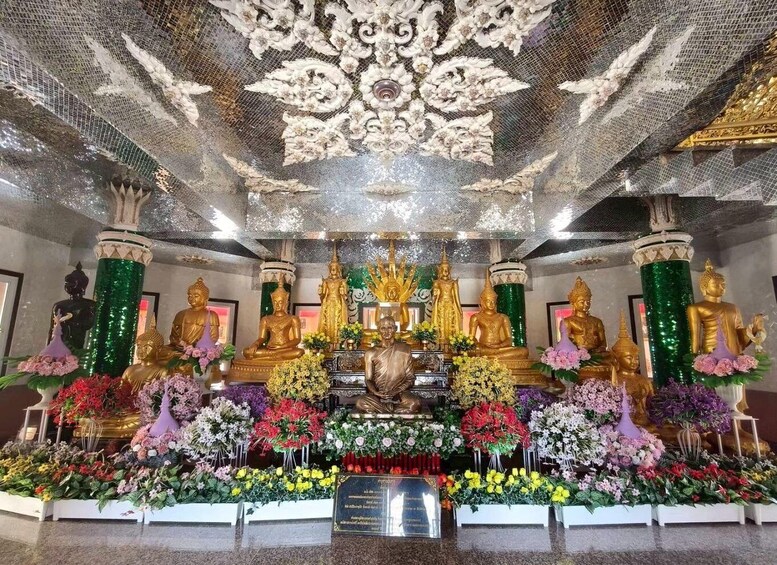 A temple interior with golden statues, floral arrangements, and ornate ceiling decorations. 3