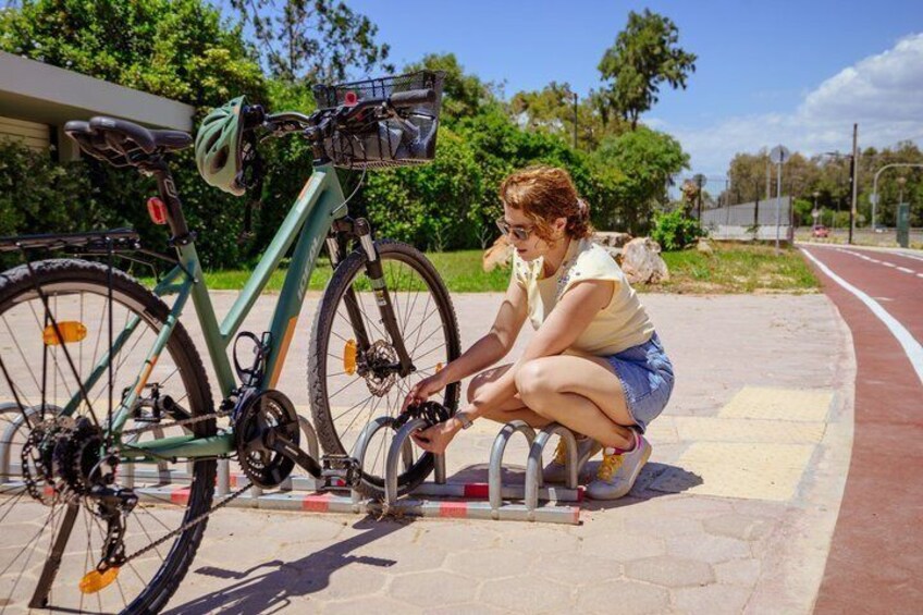 A person adjusting a bicycle on a paved path with greenery in the background. 4