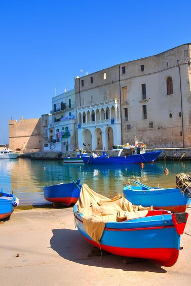 A harbor with boats, a large building with arches, and a clear blue sky. 1